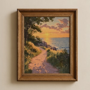May include: A framed landscape painting depicts a coastal path at sunset. The path leads towards the ocean, with a tree on the left and grassy areas along the path. The sky is filled with orange and pink hues.
