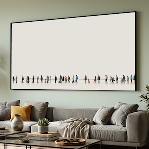 Puede incluir: Una impresión artística enmarcada que presenta una representación minimalista de una fila de personas. Las figuras son pequeñas y están silueteadas sobre un fondo color crema. La obra de arte está enmarcada en negro y cuelga sobre un sofá gris.