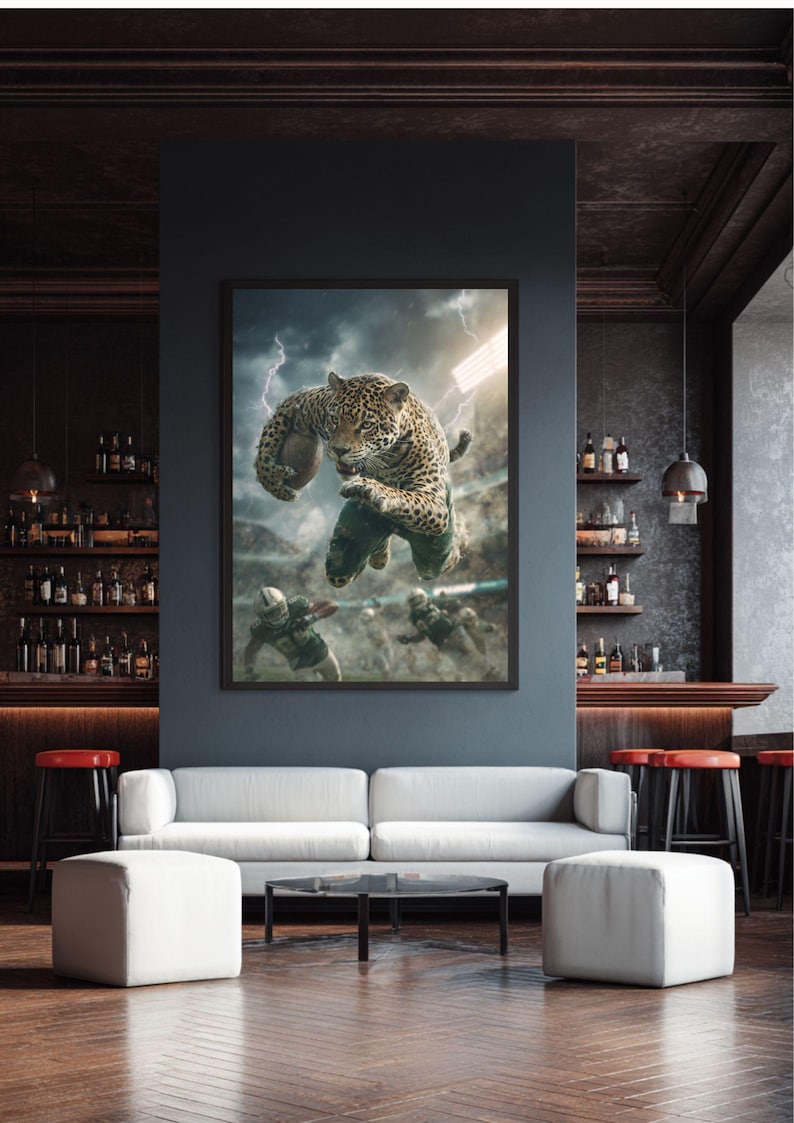 May include: Framed artwork depicting a digitally created image of a jaguar playing American football. The jaguar is leaping with the ball, with other players in the background. The artwork is displayed in a living room setting with a white sofa and dark wood flooring.