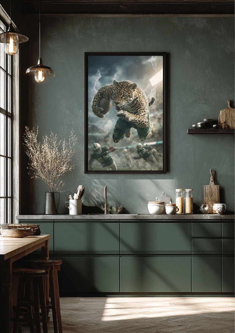 May include: Framed artwork depicting a jaguar catching a football in a dramatic football scene. The image includes a stormy sky and stadium lights. The artwork is displayed in a kitchen with dark green cabinets and a wooden table.