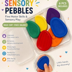 May include: A set of six colorful sensory pebbles in a clear plastic case. The pebbles are in various shapes and colors, including green, yellow, purple, blue, red, and orange. The text on the image reads "Sensory Pebbles" and "Fine Motor Skills & Sensory Play."