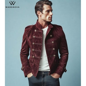 May include: A deep burgundy suede jacket featuring a double-breasted front with metallic buttons, epaulets on the shoulders, and a high collar. The jacket is worn over a plain white t-shirt and dark denim jeans. The logo WARDROVA is visible.