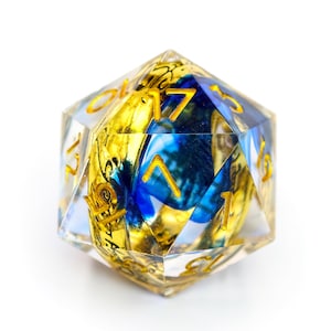 May include: A clear, multi-faceted D20 die with gold numbering and internal designs. The die features gold and blue swirls and patterns, creating a unique aesthetic. Ideal for tabletop gaming.