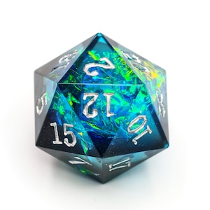 Può includere: Un dado D20 iridescente con interno blu e verde e numerazione argentata. Il dado a venti facce è progettato per giochi di ruolo da tavolo. Il dado è un oggetto suggestivo dall'aspetto complesso.