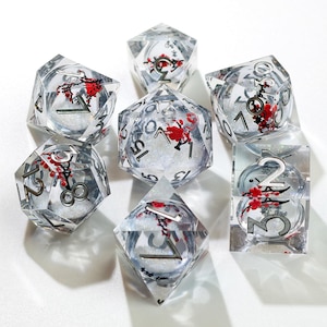 Può includere: Set di sette dadi trasparenti a più facce, con numeri argentati e motivi floreali rossi. I dadi sono riempiti di glitter. Adatti per giochi da tavolo.