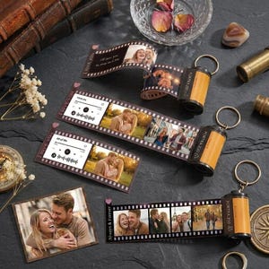 May include: Three film roll keychains with extended strips displaying printed photographs of couples and music player interfaces with the text I love you and Always & Forever. Each keychain features a metal ring attached to a plastic film canister.