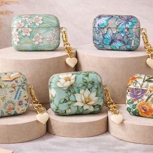 May include: Six decorative AirPod cases with floral and butterfly designs. Each case is square-shaped with a gold-colored chain and a heart-shaped charm. The cases feature various color schemes, including blue, green, and white.