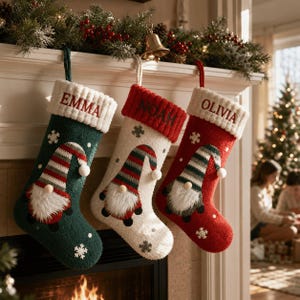 May include: Three Christmas stockings in dark green, cream, and red, each featuring a gnome with a striped hat, a white faux fur beard, and a wooden nose. The cuffs are ribbed and embroidered with the names EMMA, NOAH, and OLIVIA in red or green.