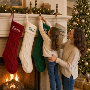 Puede incluir: Cuatro calcetines navideños de punto trenzado colgados de una repisa de chimenea. Los calcetines son rojos, blancos, verdes y beige, con nombres bordados: Emma, Noah, Lily y Oliver. Tienen un puño acanalado y un patrón texturizado.