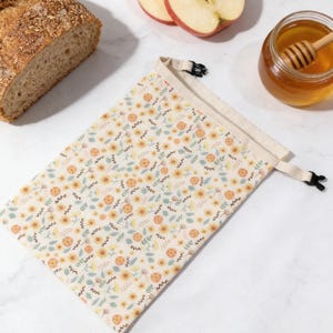 May include: A white ceramic mug with a black handle and the text "But First, Coffee" in a bold, black font. The mug is set against a blurred background, suggesting a cozy setting.