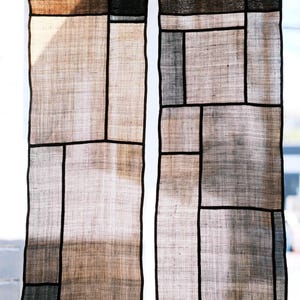 以下が含まれることがあります： 薄い茶色と灰色の半透明の正方形と長方形のパッチワークデザインが特徴の、2枚の垂直な長方形の布製パネル。細い濃い茶色のグリッド線で区切られており、並んで吊り下げられています。