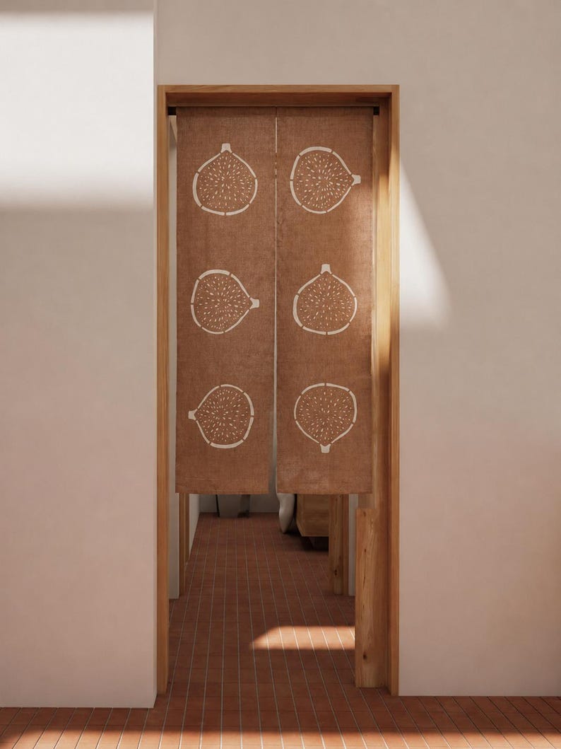 Puede incluir: Una cortina noren de tela marr&oacute;n colgada en una puerta, con un patr&oacute;n repetitivo de l&iacute;neas blancas de seis higos cortados por la mitad dispuestos en dos columnas verticales. El tejido tiene una textura visible y cuelga de un marco.