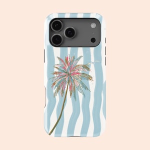 May include: A white phone case with a palm tree design. The case features a light blue wavy stripe pattern. The palm tree has pink, green, and brown details. The phone case has a camera module with three lenses.