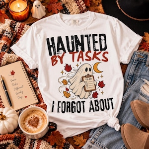 Peut inclure: Un t-shirt blanc à manches courtes avec un motif de fantôme tenant un presse-papier portant l'inscription 'TO-DO'. Le t-shirt affiche le texte noir et orange 'HAUNTED BY TASKS I FORGOT ABOUT' entouré de feuilles d'automne et d'un croissant de lune.