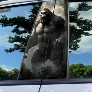 May include: A window decal featuring a detailed illustration of a gorilla in a forest setting. The gorilla is depicted with a muscular physique and an open mouth, set against a backdrop of trees and a cloudy sky.