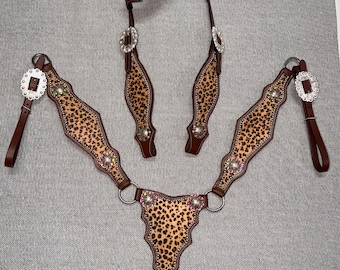 Puede incluir: Un juego completo de guarniciones para caballos con un diseño de estampado de leopardo. El juego incluye un cabezal, un peto y riendas. La guarnición es marrón con detalles plateados y pedrería decorativa.