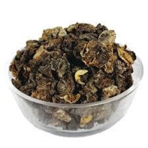 Puede incluir: Un cuenco de vidrio transparente lleno de setas secas de color marrón oscuro. Las setas tienen un aspecto texturizado e irregular, con algunas piezas más claras, de color beige. El cuenco está sobre una superficie blanca.