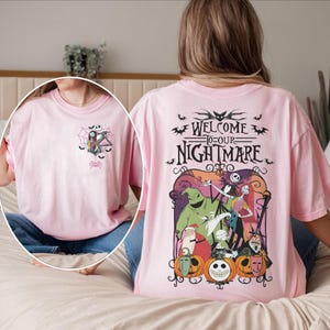 May include: A light pink t-shirt featuring a graphic from "The Nightmare Before Christmas." The front has a small design with Jack and Sally. The back displays the text "Welcome to our Nightmare" with characters and pumpkins.
