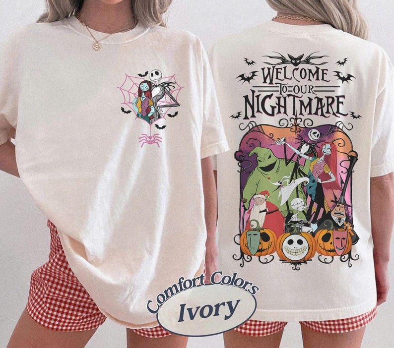 May include: Ivory-colored t-shirt featuring a graphic of Jack Skellington and Sally in a spiderweb on the front. The back of the shirt displays a colorful scene with characters and the text "WELCOME TO OUR NIGHTMARE".