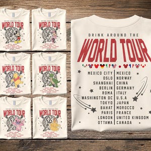 May include: A cream-colored t-shirt featuring the text Drink Around The World Tour in red, with a list of cities and countries including Mexico City, Oslo, Shanghai, Berlin, Roma, Washington DC, Tokyo, Bahat, Paris, London, and Ottawa.