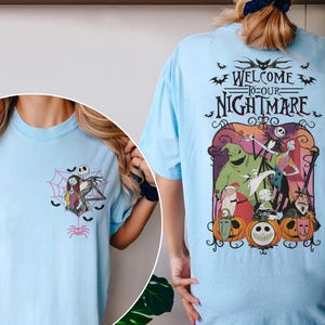 May include: Light blue t-shirts featuring graphics from "The Nightmare Before Christmas." One shirt has a small front graphic of Jack and Sally in a spiderweb. The other shirt has a large back graphic with the text "Welcome to our Nightmare."