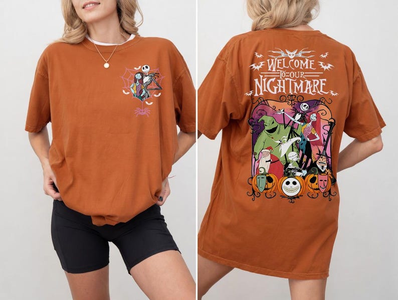 May include: Rust-colored t-shirt featuring a graphic from "The Nightmare Before Christmas." The front has a small design of Jack Skellington and Sally. The back displays a larger, colorful scene with the text "Welcome to our Nightmare."