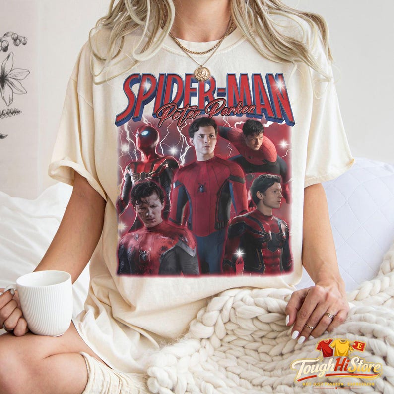 May include: Cream-colored t-shirt featuring a graphic of Spider-Man with the text "Spider-Man Peter Parker" in red and blue. The graphic includes multiple images of Spider-Man in his suit.