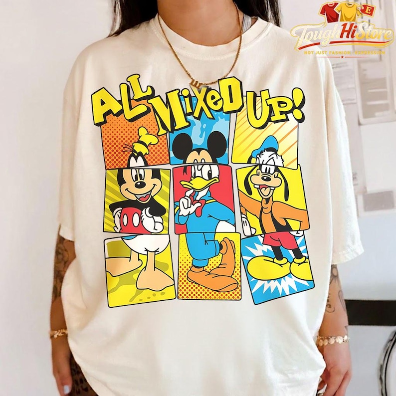Puede incluir: Camiseta color crema con un gr&aacute;fico colorido de personajes de Disney, incluyendo Mickey Mouse, el Pato Donald y Goofy. La frase "ALL MIXED UP!" est&aacute; impresa encima de los personajes en letras amarillas. La camiseta tiene mangas cortas y cuello redondo.