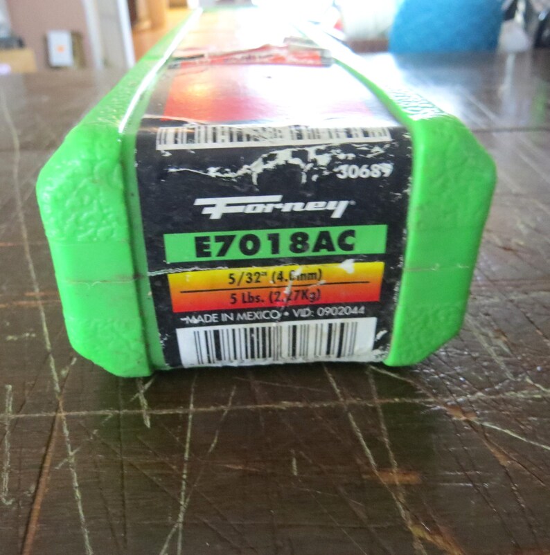 May include: A green and black package of Forney E7018AC welding rods. The label includes the size 5/32" (4.6mm) and weight 5 lbs. (2.27Kg). The package is marked "MADE IN MEXICO".