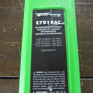 May include: A green and black label with the "Forney" logo and the text "E701-8AC". The label includes recommended amperage in English, French, and Spanish, with measurements in inches and millimeters. It also contains a warning about cancer and reproductive harm.