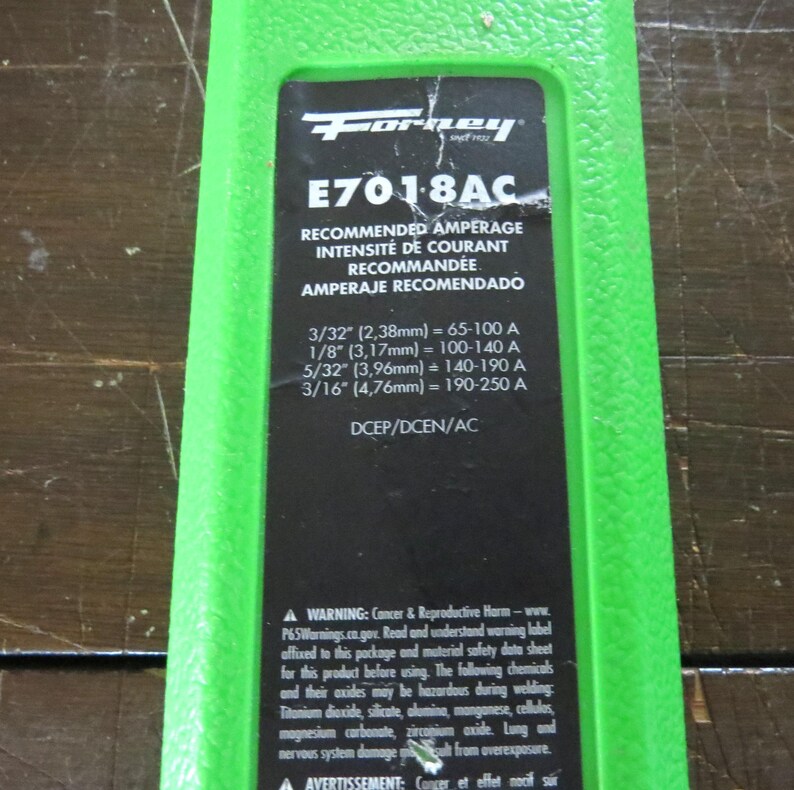 May include: A green and black label with the "Forney" logo and the text "E701-8AC". The label includes recommended amperage in English, French, and Spanish, with measurements in inches and millimeters. It also contains a warning about cancer and reproductive harm.