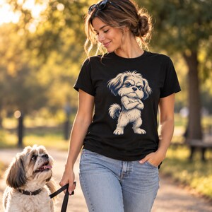 May include: A black short-sleeved t-shirt featuring a graphic illustration of a fluffy, light-colored dog with a grumpy expression and crossed arms, paired with light blue denim jeans.
