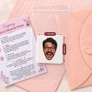 May include: A square temporary tattoo featuring a smiling person with dark hair, a beard, and glasses, measuring 2 inches by 2 inches. The set includes a printed instruction card detailing preparation, application, and removal steps for the tattoo.