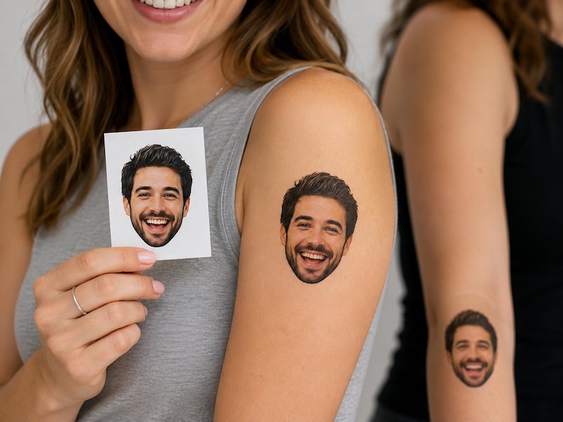 May include: A square white paper card featuring a color portrait of a smiling man with dark hair and a beard. The same portrait is applied as a temporary tattoo on the upper arm and forearm, showing the man's face with a wide, joyful expression.