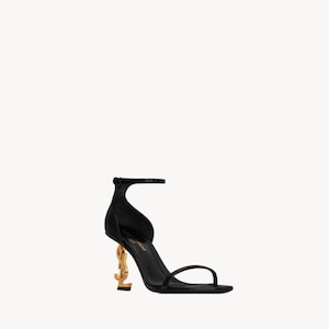 Puede incluir: Sandalia negra de tac&oacute;n alto con un tac&oacute;n dorado en forma de las letras "YSL". La sandalia tiene una fina correa en el tobillo y una sola correa en los dedos. El tac&oacute;n mide aproximadamente 10 cm de alto.