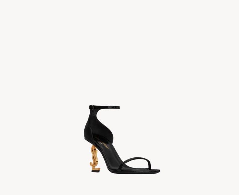 Puede incluir: Sandalia negra de tac&oacute;n alto con un tac&oacute;n dorado en forma de las letras "YSL". La sandalia tiene una fina correa en el tobillo y una sola correa en los dedos. El tac&oacute;n mide aproximadamente 10 cm de alto.