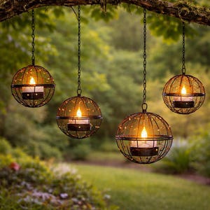 Pode incluir: Quatro lanternas esféricas suspensas com velas acesas. Cada lanterna tem um design de gaiola de metal escuro e vidro âmbar quente. As lanternas são suspensas de um galho de árvore por correntes, criando um brilho suave e convidativo.