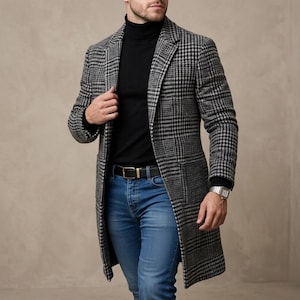 Könnte beinhalten: Ein langer, grau-schwarz karierter Mantel mit schwarzem Rollkragenpullover, blauer Jeans und einem schwarzen Gürtel mit goldener Schnalle. Der Mantel hat zwei Vordertaschen. Eine silberne Uhr ist sichtbar.