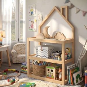 May include: A wooden house-shaped bookshelf with three shelves. The top shelf features wooden cloud and crescent moon decorations. The shelves are filled with toys, books, and storage boxes. The room has a rug, a small chair, and children's drawings on the wall.