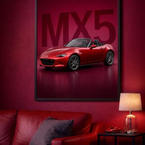 Puede incluir: Impresión enmarcada de un coche descapotable Mazda MX-5 rojo. El coche se muestra sobre un fondo rojo con el texto "MX5" en letras grandes. La imagen está en una habitación con paredes rojas y un sofá de cuero rojo.