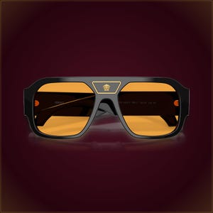 May include: Black sunglasses with a thick frame and orange-tinted lenses. A gold-tone Medusa head emblem is centered on the bridge. The frame features a flat top bar, and the Versace logo is printed on the inner temple arm in a gold-tone font.