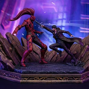 May include: A detailed figurine depicting a battle scene. One figure is clad in red armour, the other in black, both poised with weapons. The base is a rocky terrain with ornate detailing, set against a purple and blue background.