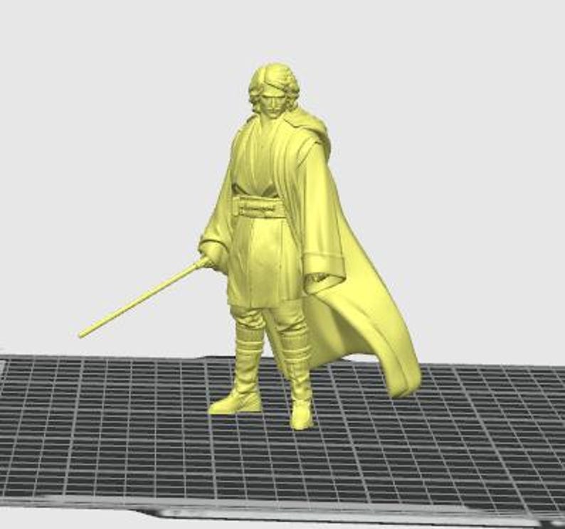 Pu&ograve; includere: Una statuetta gialla di un personaggio di un franchise di fantascienza, che indossa un lungo mantello e tiene una spada laser. La figura &egrave; in piedi su una superficie grigia a griglia. Il personaggio indossa stivali e una cintura.