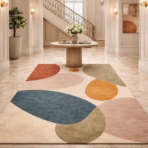 Handmade abstract wool rug with scalloped edges featuring organic shapes in rust, beige, ivory, grey, and charcoal tones on wooden floor in modern living room setting