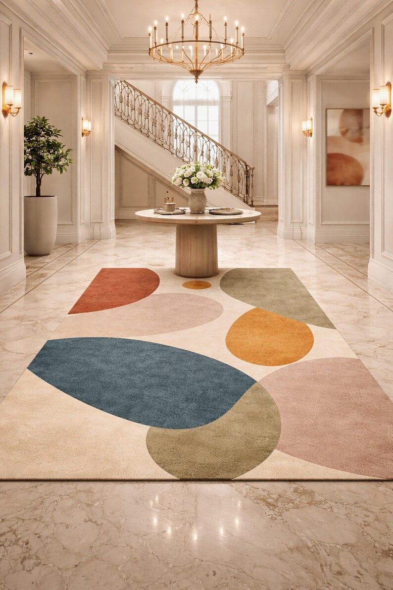 Handmade abstract wool rug with scalloped edges featuring organic shapes in rust, beige, ivory, grey, and charcoal tones on wooden floor in modern living room setting