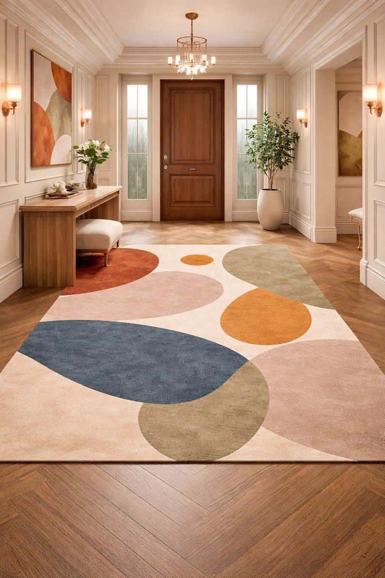 Handmade abstract wool rug with scalloped edges featuring organic shapes in rust, beige, ivory, grey, and charcoal tones on wooden floor in modern living room setting
