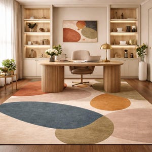 Handmade abstract wool rug with scalloped edges featuring organic shapes in rust, beige, ivory, grey, and charcoal tones on wooden floor in modern living room setting