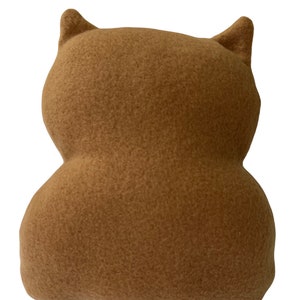 May include: A brown plush toy shaped like an owl with large ears. The owl is made of soft, fuzzy fabric.