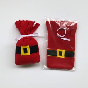 May include: Two red felt Christmas stocking ornaments with black and gold belts. The ornaments are packaged in a clear plastic bag.