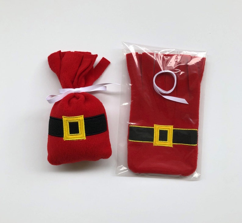 May include: Two red felt Christmas stocking ornaments with black and gold belts. The ornaments are packaged in a clear plastic bag.